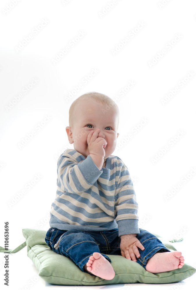 Sweet boy infant eat his finger smiling sit on green pillow isol Sweet boy infant eat his finger smiling sit on green pillow isol