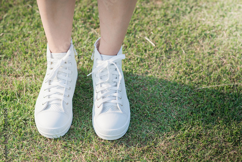 woman in white sneakers walking under sunlight