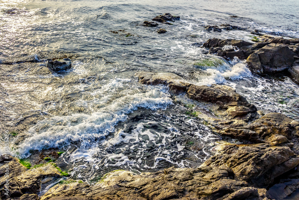 wave rolls onto the rocks of sandy coast