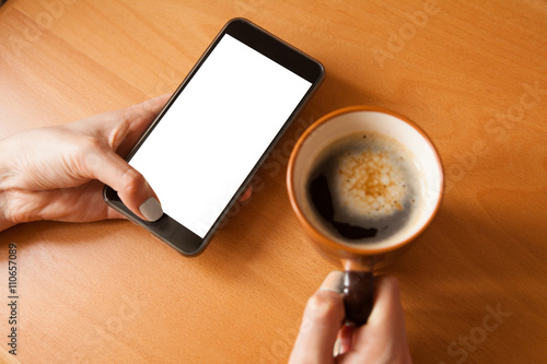 Mobile phone mockup. Female hands with smartphone with copy space on screen and cup of coffee. Mobile phone with blank screen.