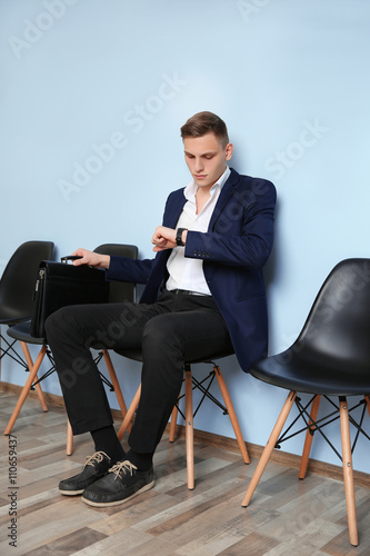 Young man in suit sitting on chair and waiting for job interview