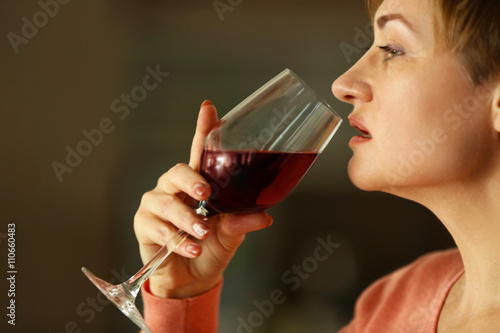 Beautiful middle-aged woman tasting red wine, close-up