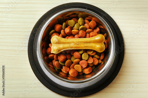 Dog food in metal bowl on wooden background
