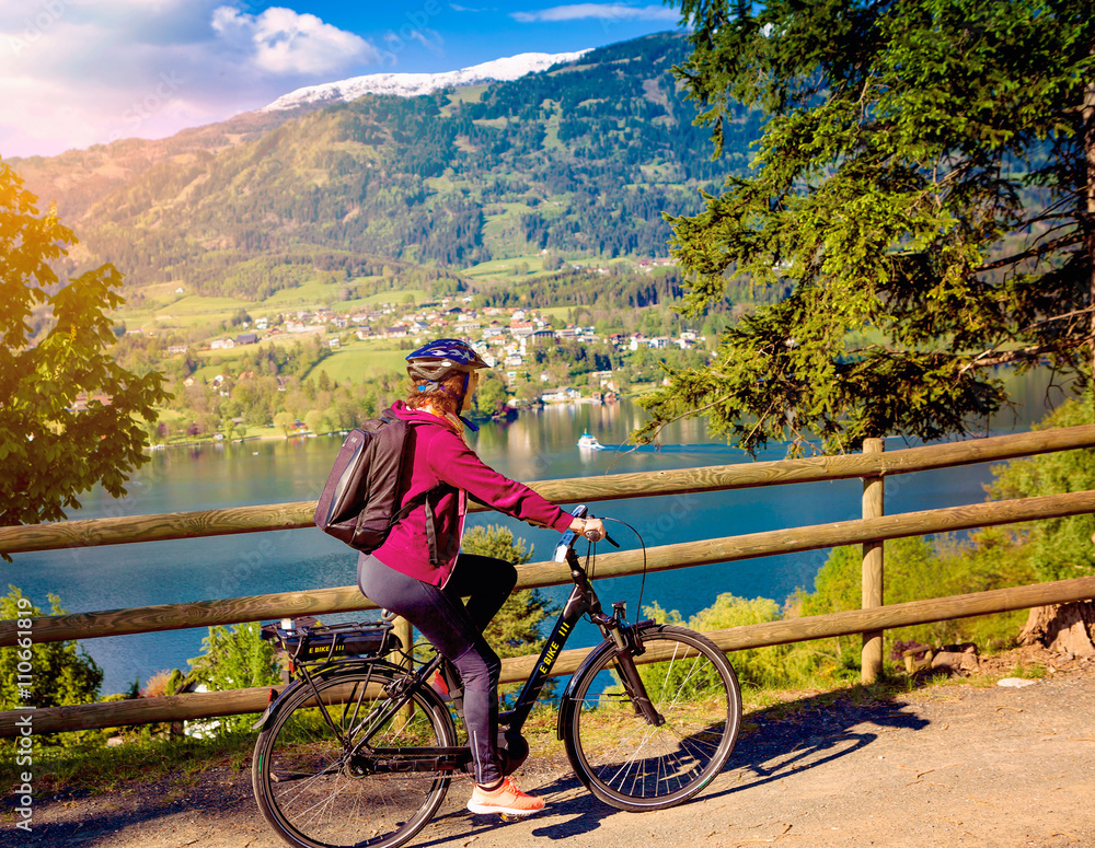 Fototapeta premium woman with e-bike cycling beside a beautiful lake-lake and bike