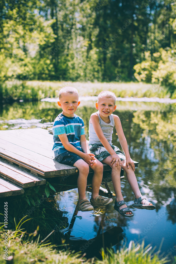 Two little boys friends sits outdoors in nature Two little boys friends sits outdoors in nature