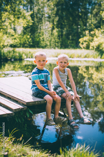 Two little boys friends sits outdoors in nature © cmirnovalexander