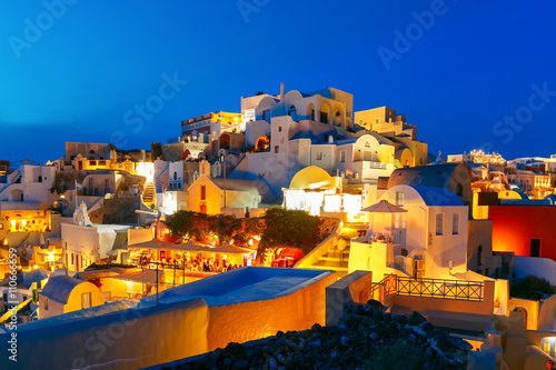 Old Town of Oia on the island Santorini, white houses and church with blue domes during twilight blue hour, Greece
