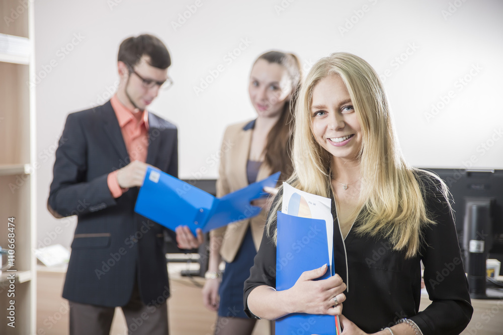 a girl student smiling on the background of young business people in office a girl student smiling on the background of young business people in office