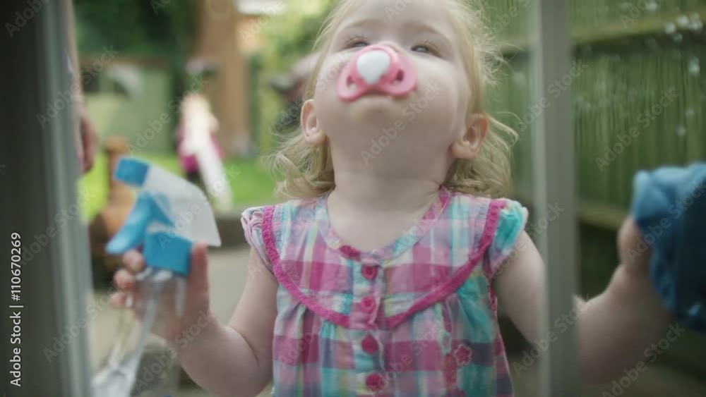 Cute little girl with cleaning cloth cleaning window from outside Cute little girl with cleaning cloth cleaning window from outside