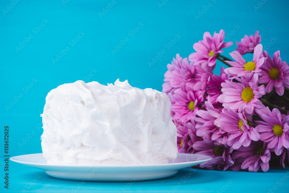 White creamy cake with flowers on the blue wooden background White creamy cake with flowers on the blue wooden background