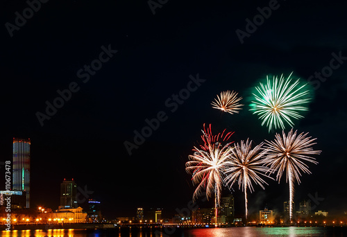 colored flashes of fireworks over the city pond of Yekaterinburg in the city center © vladimircaribb
