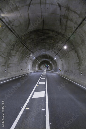 landscape straight grey lonely road tunnel with two lanes, white painting dividing lines in asphalt and light, in Spain Europe