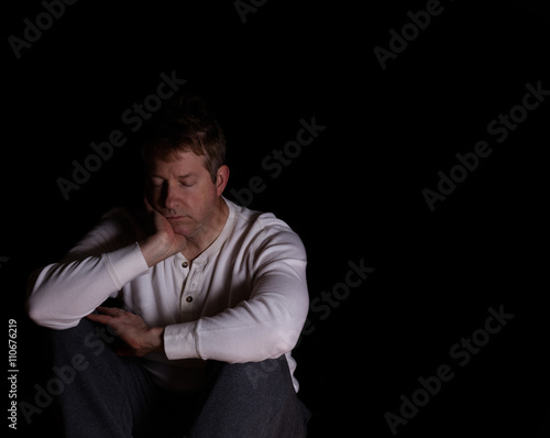 Mature man showing depression while sitting down in the darkness © tab62