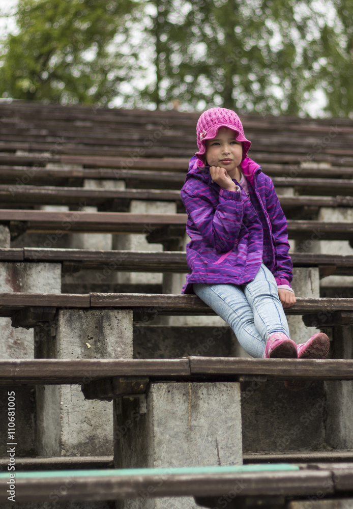 Sad little girl is sitting on the bench