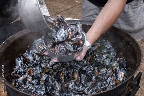 Chef with mussels in cauldron