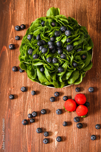 Fototapeta Naklejka Na Ścianę i Meble -  Fresh lettuce with blueberry, lemon and strawberries on a wooden