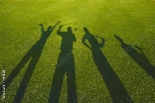 Four golfers with open hands silhouette on grass 