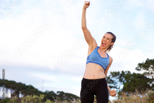 Excited sports woman cheering with arms raised