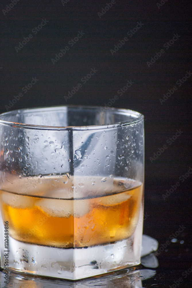 Whiskey Glass - Scotch Glass with ice cubes with background and shinny reflection on bottom Whiskey Glass - Scotch Glass with ice cubes with background and shinny reflection on bottom