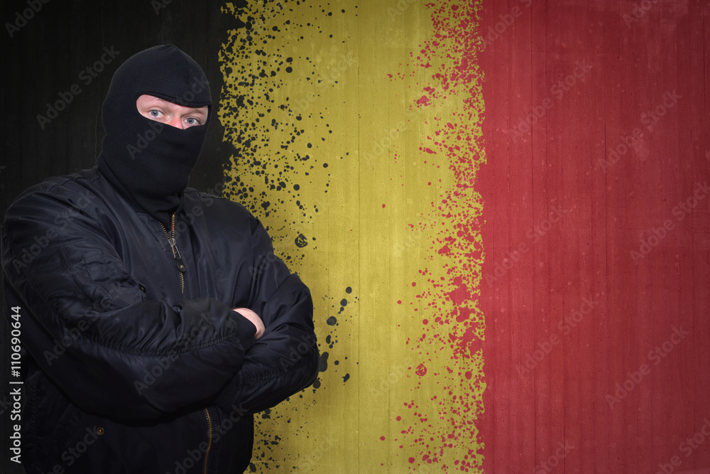 dangerous man in a mask standing near a wall with painted national flag of belgium dangerous man in a mask standing near a wall with painted national flag of belgium