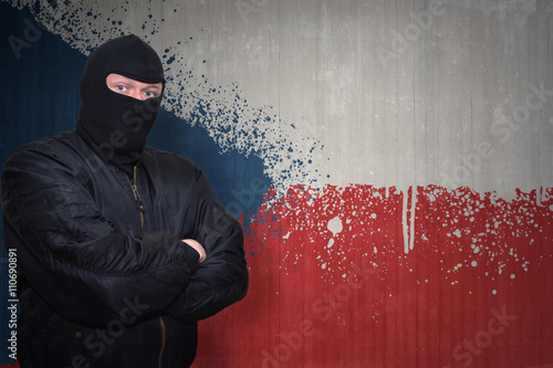 dangerous man in a mask standing near a wall with painted national flag of czech republic