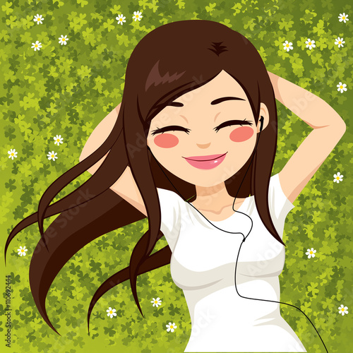 Beautiful brunette woman relaxed lying on grass field listening to music with eyes closed