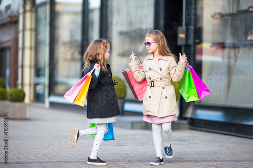 Adorable little girls on shopping. Portrait of kids with shopping bags. 