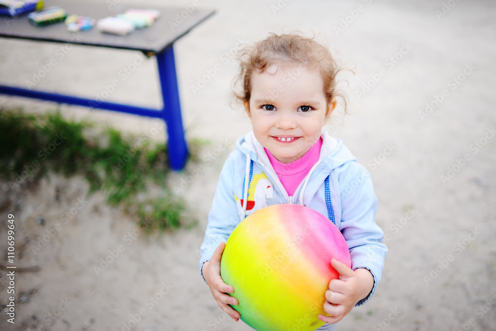 baby girl playing with a colored ball in the playground baby girl playing with a colored ball in the playground