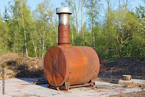 old iron stove with a chimney. rusty stove with a chimney in the park. iron wood-burning stove. limited depth of field. sunset warm light.