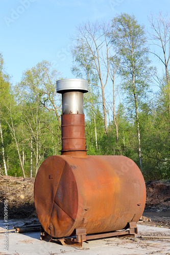 old iron stove with a chimney. rusty stove with a chimney in the park. iron wood-burning stove. limited depth of field. sunset warm light.
