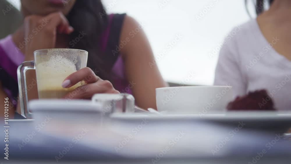 Female friends chatting at outdoor cafe table in the city Female friends chatting at outdoor cafe table in the city