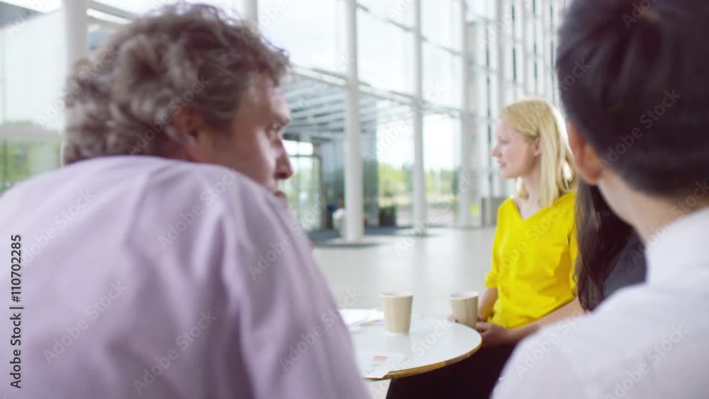 Mixed ethnicity business group chatting in large modern office building Mixed ethnicity business group chatting in large modern office building