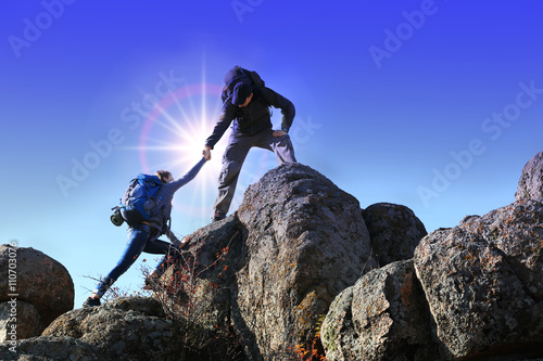 Helping hands with sunlight between two climbers