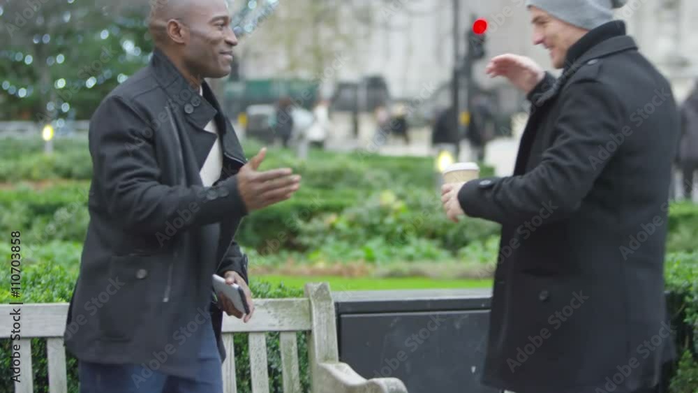 Happy casual male friends meet up and greet each other outdoors in the city Happy casual male friends meet up and greet each other outdoors in the city