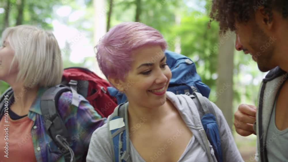 Group of friends hiking in the woods putting on backpacks and preparing to walk Group of friends hiking in the woods putting on backpacks and preparing to walk