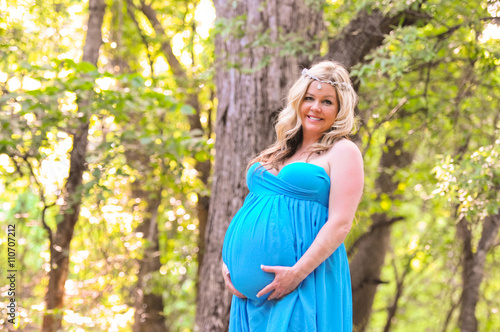 Beautiful pregnant woman in teal dress outdoors.