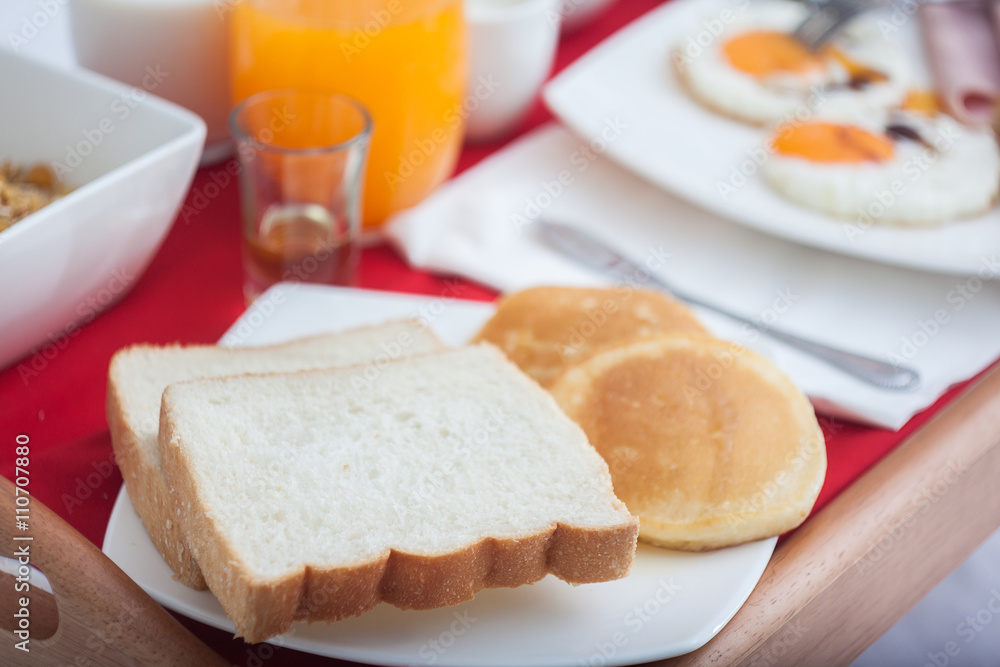 Breakfast set in wooden tray on bed Breakfast set in wooden tray on bed