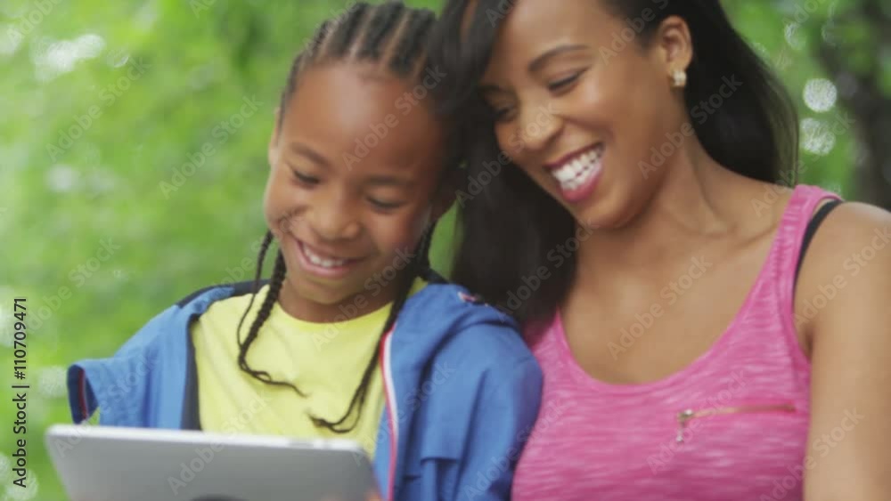 Happy African American mother & son, relaxing in the park & looking at computer tablet. Happy African American mother & son, relaxing in the park & looking at computer tablet.