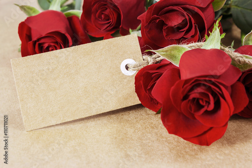 Fototapeta Naklejka Na Ścianę i Meble -  Red roses with blank paper tag on brown paper