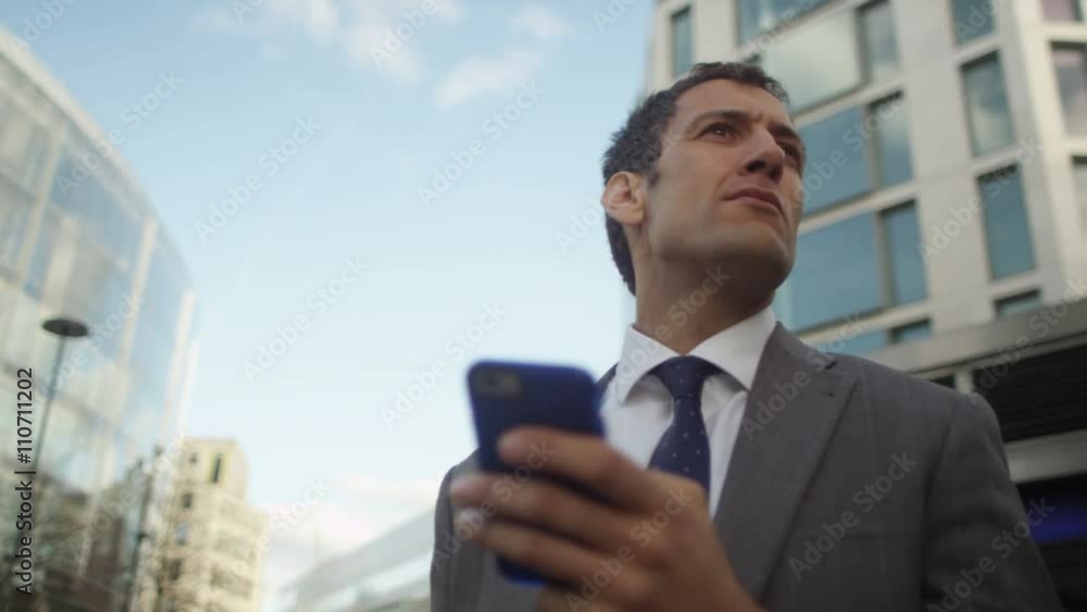 Attractive businessman using smartphone for navigation outdoors in the city Attractive businessman using smartphone for navigation outdoors in the city