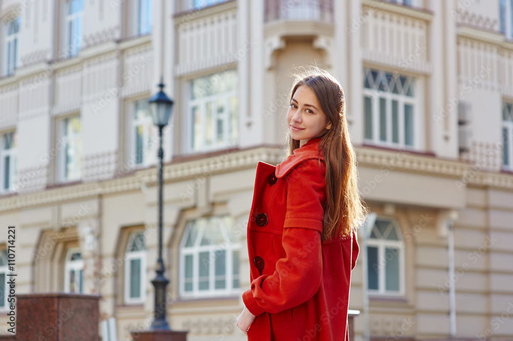 young beautiful woman in red coat in the city