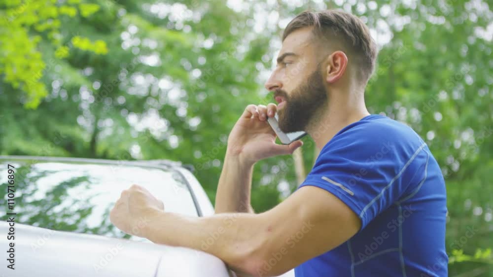 Young man in fitness clothing making mobile phone call beside his car. Young man in fitness clothing making mobile phone call beside his car.