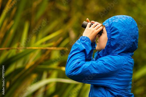 young boy bird watching in a forest photo