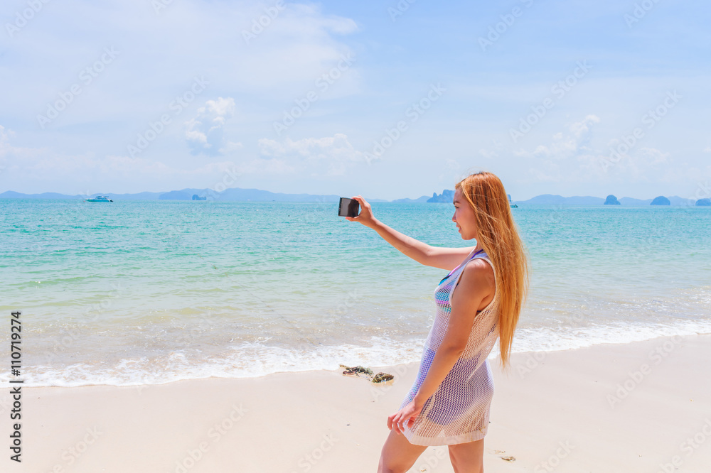 Happy attractive blonde in bikini taking a self picture on a beautiful sunny beach
