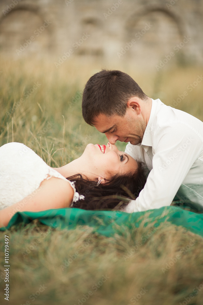 Happy wedding couple lying on green grass at the summer time Happy wedding couple lying on green grass at the summer time