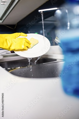 Woman washing plate at kitchen sink