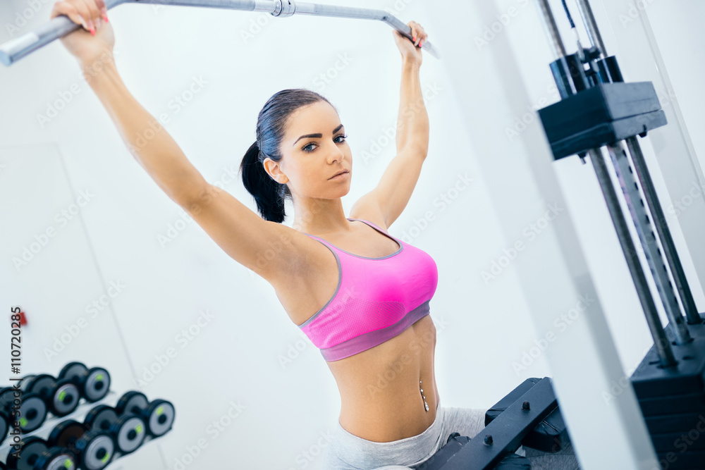 Beautiful and attractive young woman doing exercises at fitness gym.