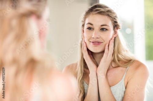 Happy young woman looking in mirror 