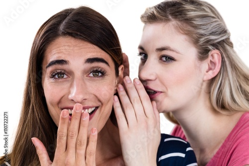Woman whispering in friend ear 