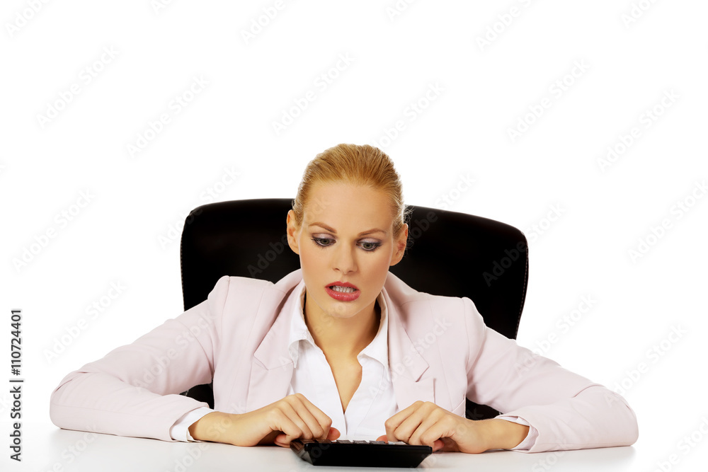 Young smile business woman sitting behind the desk and using calculator Young smile business woman sitting behind the desk and using calculator